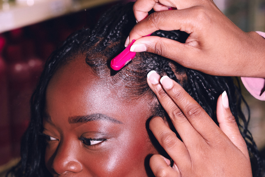 Person styling another person's hair with a pink comb.